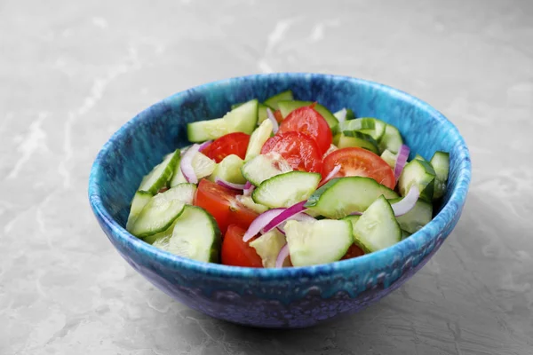 Schüssel vegetarischer Salat mit Gurken, Tomaten und Zwiebeln auf dem Tisch — Stockfoto
