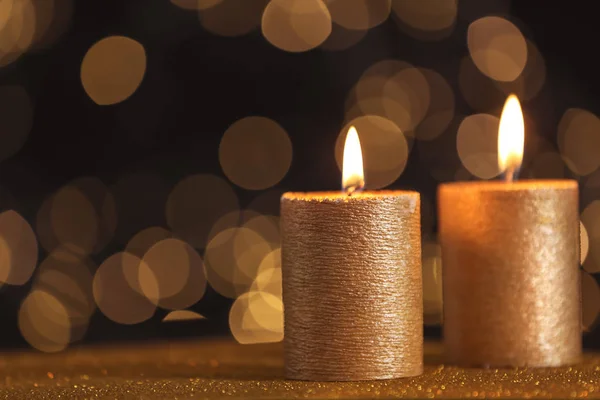 Queimar velas de ouro na mesa contra luzes turvas. Espaço para texto — Fotografia de Stock