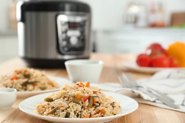 Delicious rice with vegetables and multi cooker on wooden table — Stock Photo, Image