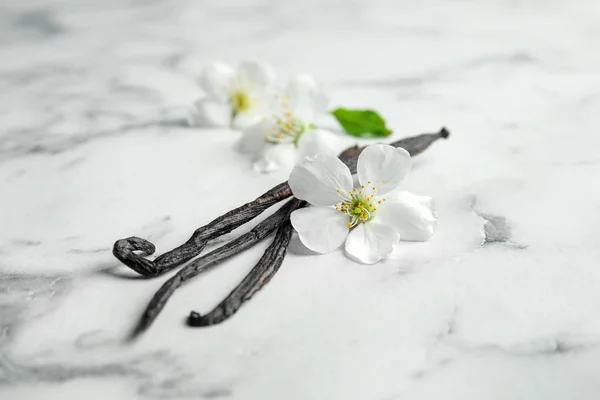 Aromatische Vanillestangen und Blumen auf Marmorhintergrund — Stockfoto