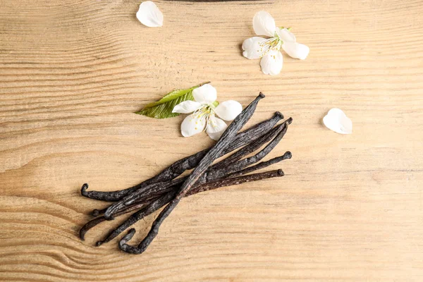 Composición plana con varillas de vainilla aromáticas y flores sobre fondo de madera — Foto de Stock