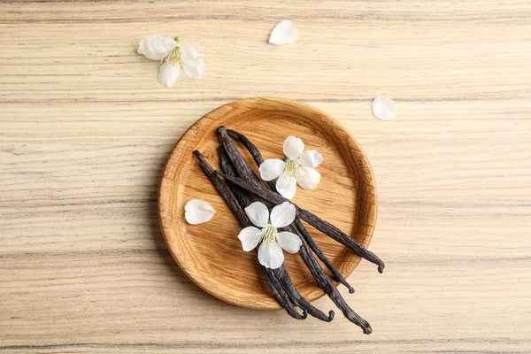 Composición plana con varillas de vainilla aromáticas y flores sobre fondo de madera — Foto de Stock