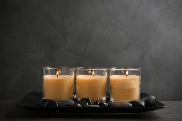 Tmavá deska se třemi hořícími svíčkami na stole — Stock fotografie