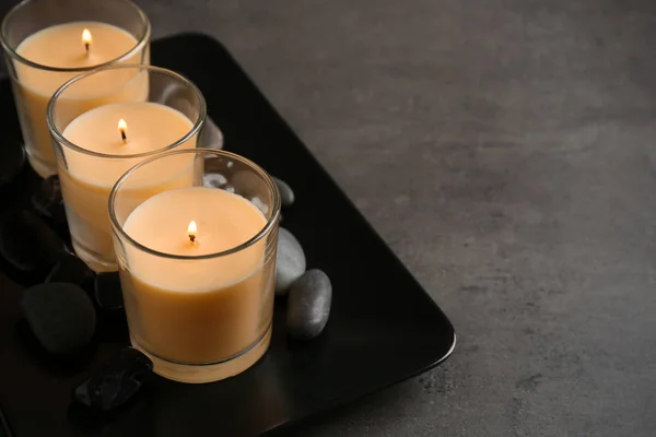 Placa escura com três velas e pedras acesas na mesa, espaço para texto — Fotografia de Stock