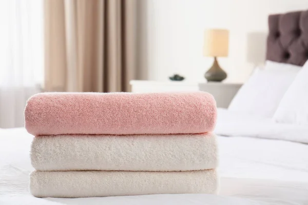 Stack of folded soft towels on bed in room. Space for text — Stock Photo, Image