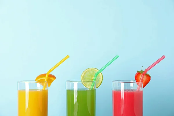 Tre bicchieri con diversi succhi e cannucce su sfondo a colori — Foto Stock