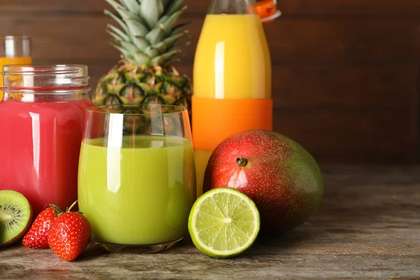 Glas med olika juicer och färsk frukt på trä bakgrund. Utrymme för text — Stockfoto