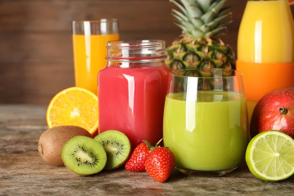 Artículos de vidrio con diferentes jugos y frutas frescas sobre fondo de madera — Foto de Stock