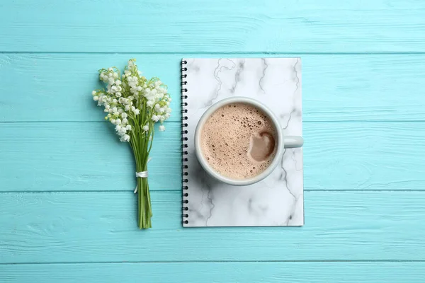 Platte lay samenstelling met notebook, Lily of the Valley boeket en koffie op houten achtergrond — Stockfoto
