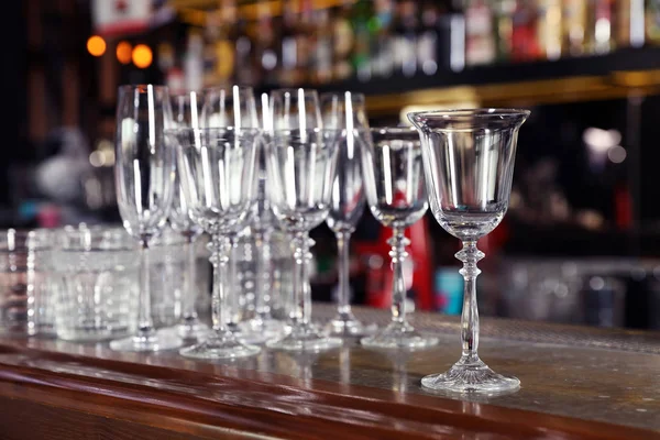 Different empty clean glasses on counter in bar Royalty Free Stock Photos