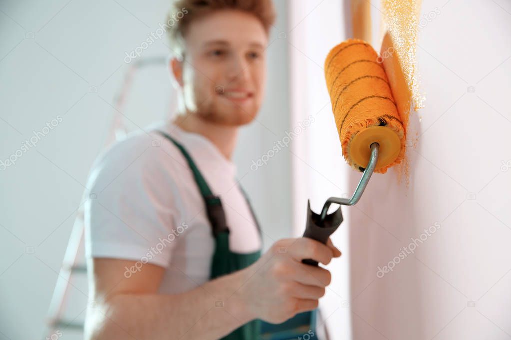 Professional decorator painting wall indoors. Home repair service