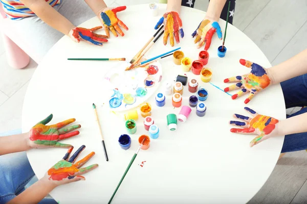 Lindos niños pequeños mostrando las manos pintadas en la lección en el interior, vista superior — Foto de Stock