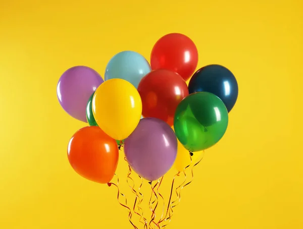 Manojo de globos brillantes sobre fondo de color. Tiempo de celebración — Foto de Stock