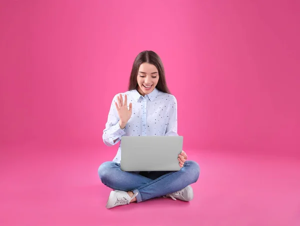 Femme utilisant un ordinateur portable pour le chat vidéo sur fond couleur — Photo
