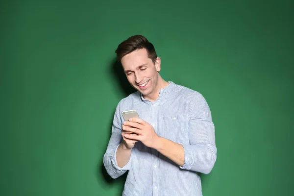 Retrato de homem bonito com telefone celular em fundo de cor — Fotografia de Stock