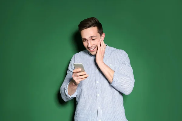 Portrait de l'homme émotionnel avec téléphone portable sur fond de couleur — Photo