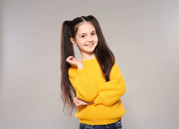 Porträt eines kleinen Mädchens posiert auf grauem Hintergrund — Stockfoto
