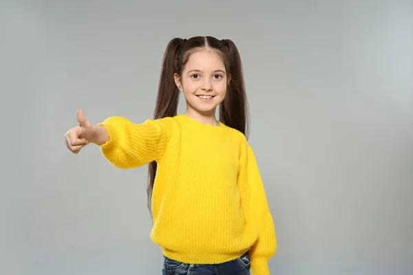 Portrét malé holčičky, která pózala na šedém pozadí — Stock fotografie