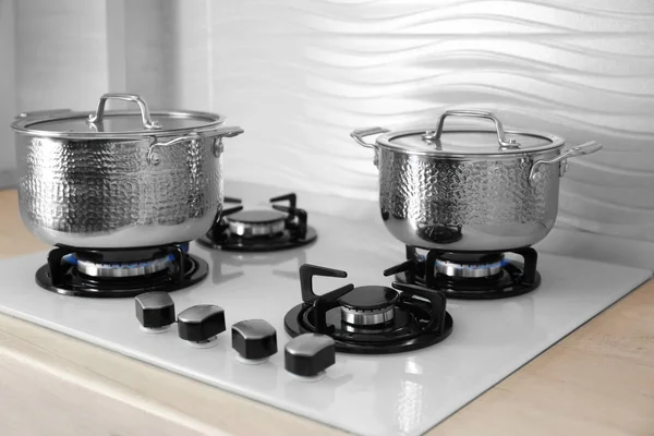 Shiny steel saucepans on modern gas stove — Stock Photo, Image