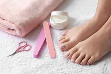 Güzel ayakları ve beyaz havluyla pedikür aksesuarları olan bir kadın, yakın plan. Spa tedavisi