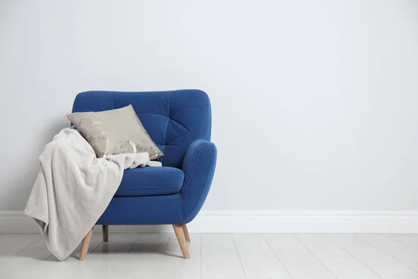 Стильное кресло с подушкой и клеткой возле белой стены, место для текста. Дизайн интерьера — стоковое фото