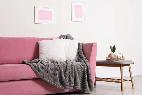 Gemütliches Wohnzimmerinterieur mit Sofa, Kissen und Plaid in der Nähe der hellen Wand — Stockfoto