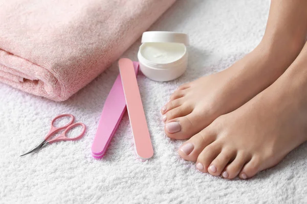 Güzel ayakları ve beyaz havluyla pedikür aksesuarları olan bir kadın, yakın plan. Spa tedavisi