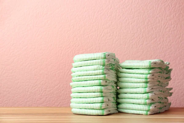 Stacks of diapers on table against color background, space for text. Baby accessories — Stock Photo, Image