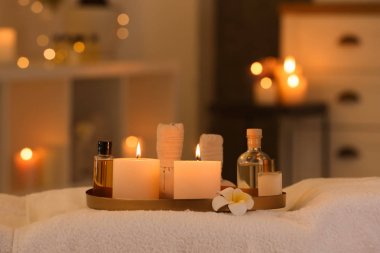 Spa salonunda masaj masasında kozmetik ve yanan mumlar