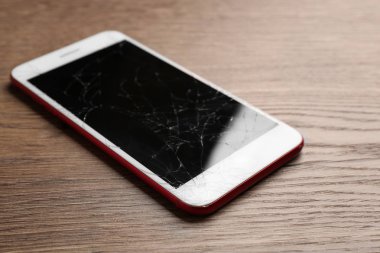 Masada kırık ekrana sahip modern akıllı telefon. Cihaz onarım hizmeti