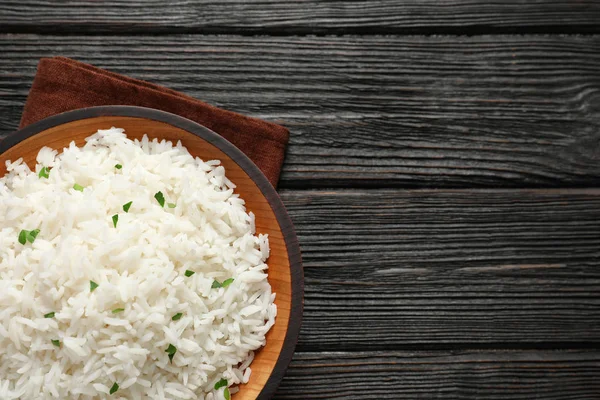 Plate of tasty cooked rice on wooden background, top view. Space for text