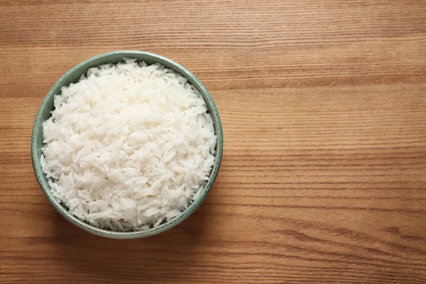 Cuenco de sabroso arroz cocido sobre fondo de madera, vista superior. Espacio para texto — Foto de Stock