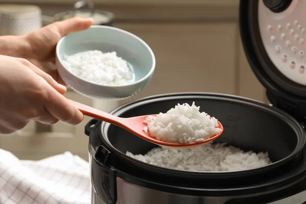 Женщина кладет вкусный рис в миску из плиты на кухне, крупным планом — стоковое фото