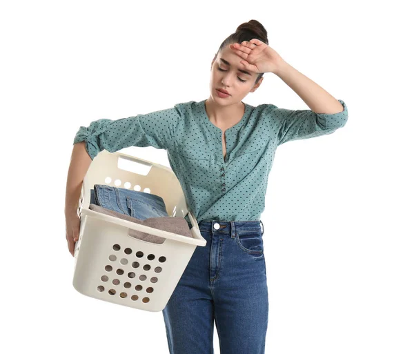Mujer joven cansada sosteniendo cesta con lavandería sobre fondo blanco — Foto de Stock