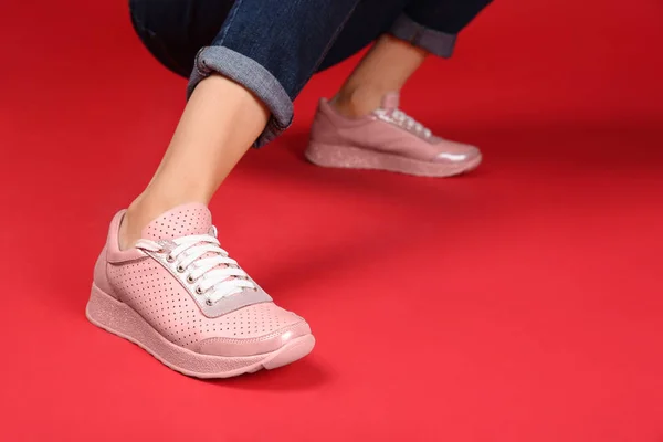 Mulher em sapatos esportivos elegantes no fundo de cor — Fotografia de Stock