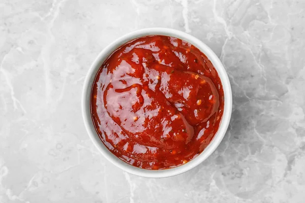 Miska s horkou chilli omáčkou na mramorovém pozadí, pohled shora — Stock fotografie