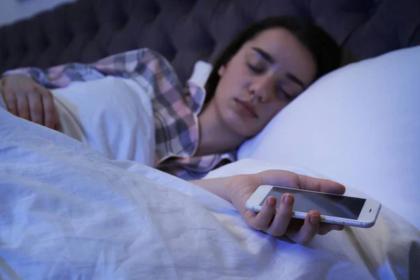 Одинокая женщина спит со смартфоном в постели, крупным планом — стоковое фото