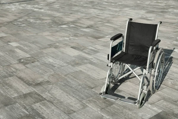 Άδειο αναπηρικό αμαξίδιο σε εξωτερικούς χώρους την ηλιόλουστη μέρα. Χώρος για κείμενο — Φωτογραφία Αρχείου