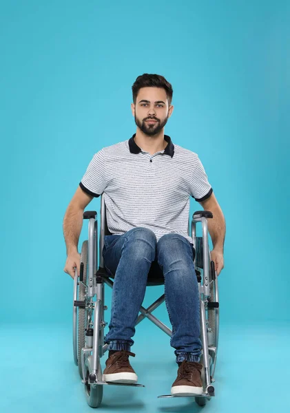Młody człowiek na wózku inwalidzkim na kolor tła — Zdjęcie stockowe