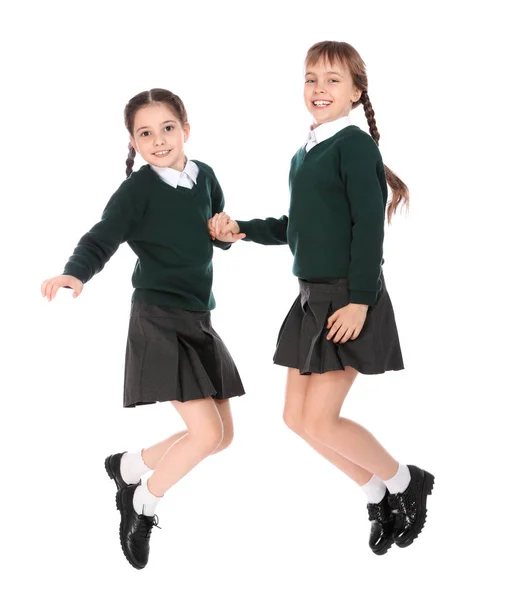 Chicas lindas en uniforme escolar saltando sobre fondo blanco —  Fotos de Stock
