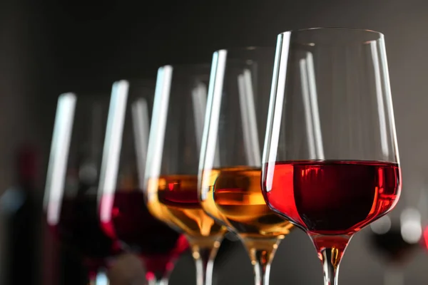 Row of glasses with different wines against blurred background, closeup — Stock Photo, Image