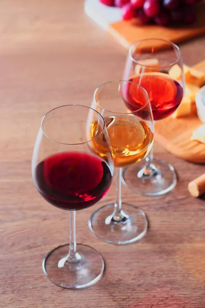 Copos com diferentes vinhos e aperitivos em mesa de madeira — Fotografia de Stock