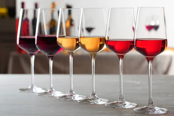 Row of glasses with different wines on table against blurred background — Stock Photo, Image