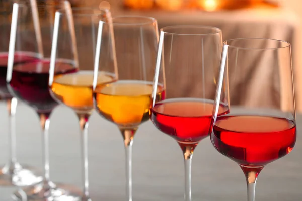 Reihe von Gläsern mit verschiedenen Weinen vor verschwommenem Hintergrund, Nahaufnahme — Stockfoto
