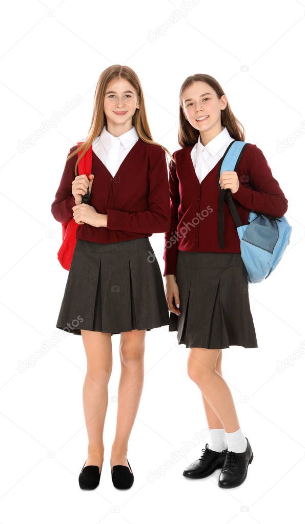 Full length portrait of teenage girls in school uniform with backpacks on white background