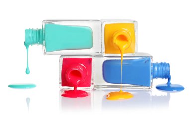 Beyaz arka plan üzerinde şişe ile dökülen farklı ojeler