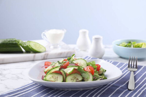 Plate of vegetarian salad with cucumber, tomato, lettuce and onion served on table