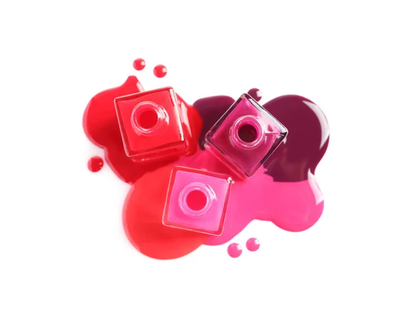 Spilled different nail polishes with bottles on white background, top view — Stock Photo, Image