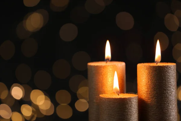 Quemando velas de oro contra luces borrosas en la oscuridad. Espacio para texto — Foto de Stock