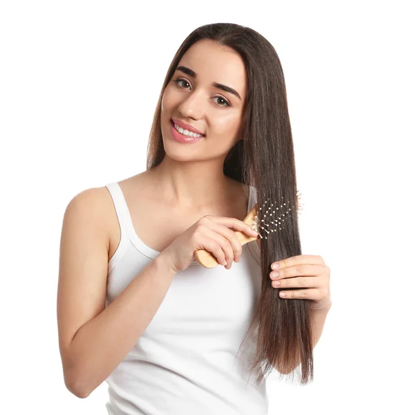 Bella giovane donna con spazzola per capelli su sfondo bianco — Foto Stock